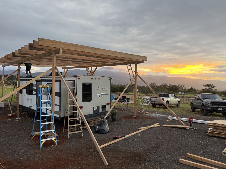 Large timber shade structure framing at sunset
